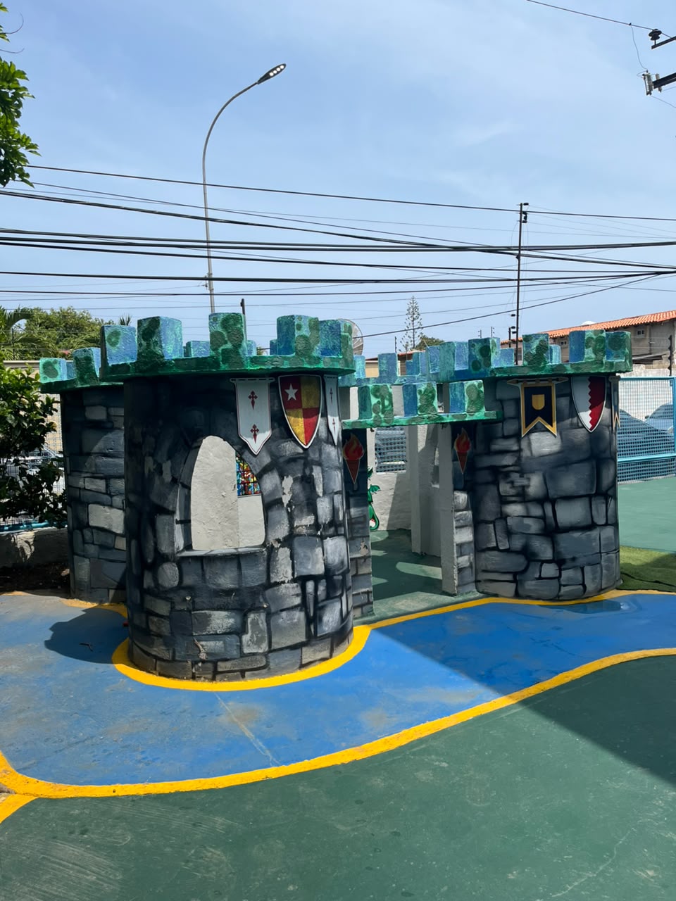 Castillo de juegos con torres almenadas y escudos pintados